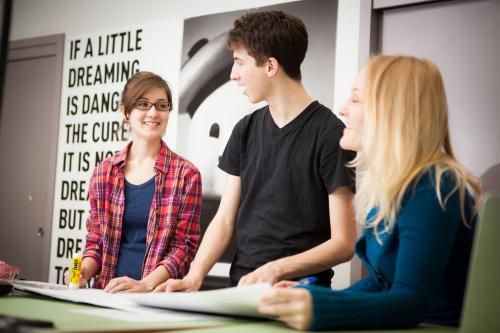 3 Graphic Design students standing in a classroom and talking